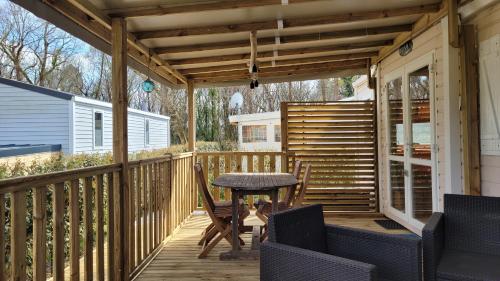 un patio avec une table et des chaises sur une terrasse dans l'établissement Joli Mobilhome 4 personnes proche Mimizan océan et lac, à Sainte-Eulalie-en-Born