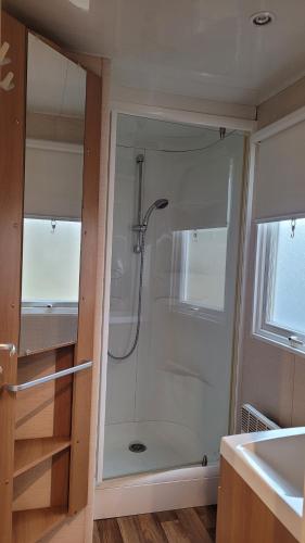 a shower with a glass door in a bathroom at Joli Mobilhome 4 personnes proche Mimizan océan et lac in Sainte-Eulalie-en-Born