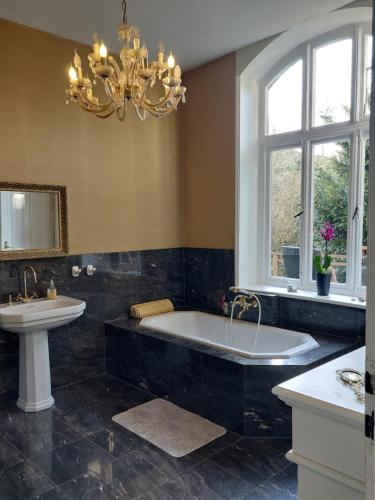 a bathroom with a tub and a sink and a chandelier at Villa Elisabeth 1905 in Bad Harzburg