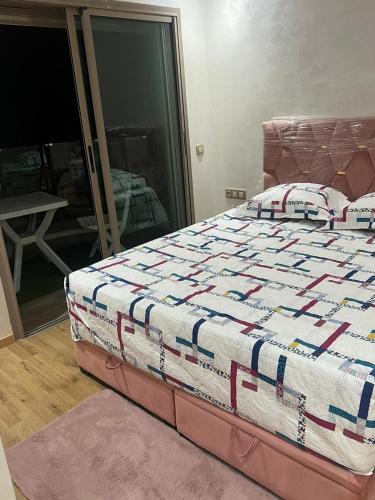 a bed with a quilt on it in a bedroom at appartement de lux vue piscine 5 min plage bouznika in Bouznika