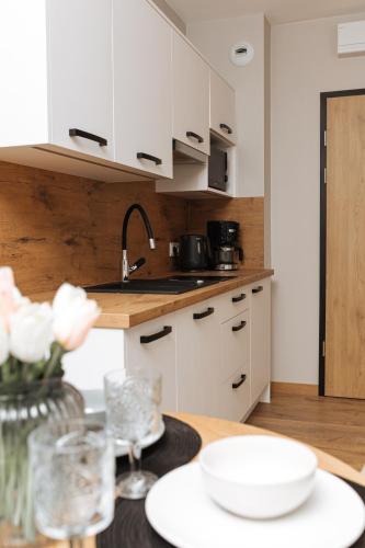 a kitchen with white cabinets and a table with flowers at Apartamenty IDA - Belle View in Szklarska Poręba