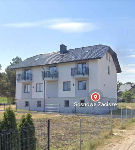 a white building with a sign in front of it at Sosnowe Zacisze - Pokoje Gościnne Blisko Jeziora in Swornegacie