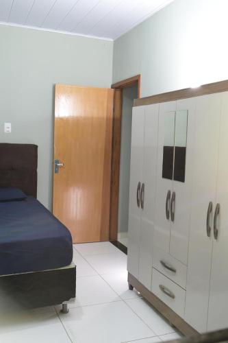 a bedroom with a bed and a dresser and a door at Residential House in Anápolis in Anápolis