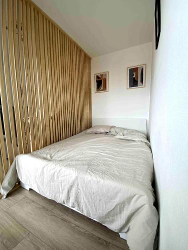 Ce lit se trouve dans une chambre dotée d'un mur en bois. dans l'établissement Magnifique Vue à 2 pas de la plage, à Saint-Hilaire-de-Riez