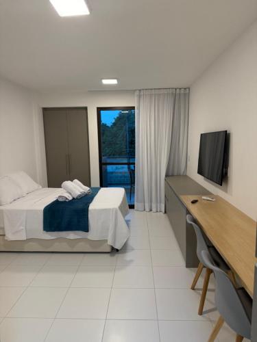 a bedroom with a bed and a desk and a television at Malia Beach in Ipojuca