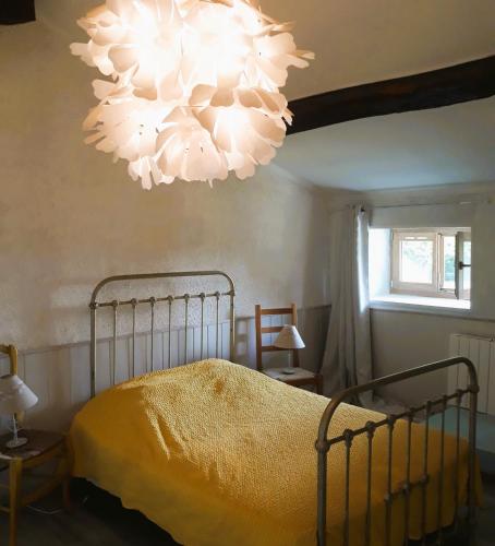 une chambre avec un lit et un lustre dans l'établissement Un jardin sur la colline, à Claveyson