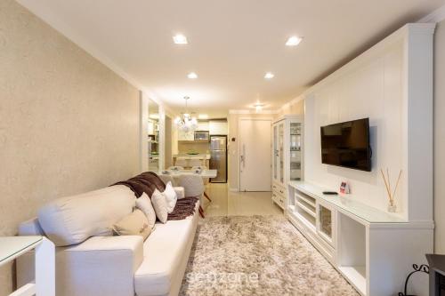 a living room with a white couch and a tv at Apto Aconchegante no Centro de Canela | CPL025 in Canela