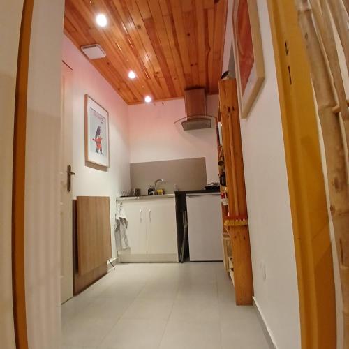 une cuisine avec des armoires blanches et un plafond en bois dans l'établissement Studio au cœur de la nature, à Saint-Paul-en-Born