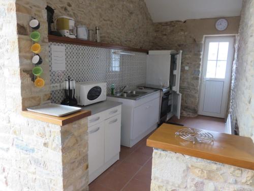 La cuisine est équipée de placards blancs, d'un évier et d'un comptoir. dans l'établissement La Pigacherie aux Pierres Bleues, à Surtainville