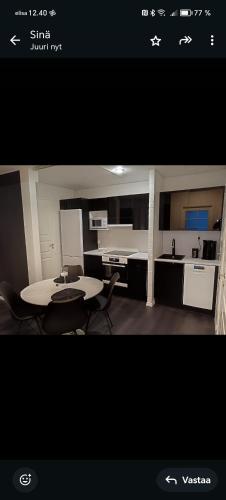 a room with a table and chairs and a kitchen at Salon Harlekiini in Lieksa