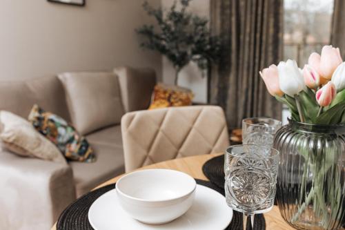 a table with a vase of pink tulips in a living room at Apartamenty IDA - Belle View in Szklarska Poręba