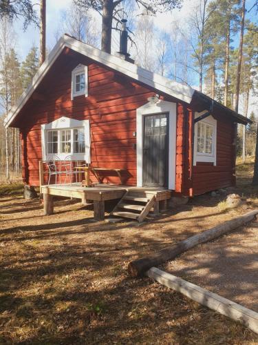 a cabin in the woods with a porch and a window at Härbre Åsbacka in Bollnäs