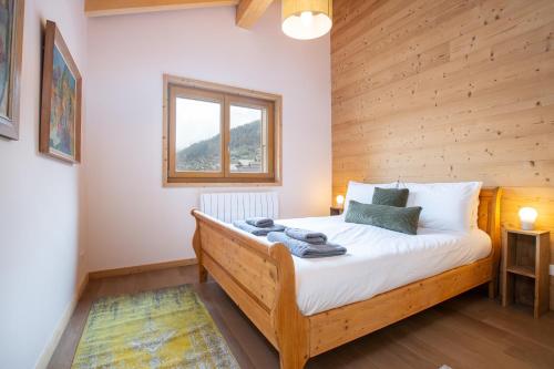 - une chambre avec un lit et un mur en bois dans l'établissement Large, bright and comfortable 3 bedroom apartment, à Morzine