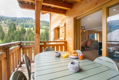 une table à manger sur une terrasse avec vue sur les montagnes dans l'établissement Large, bright and comfortable 3 bedroom apartment, à Morzine