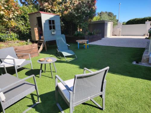 une cour avec des chaises de jardin, une table et une maison dans l'établissement La petite maison, à La Celle-sous-Gouzon