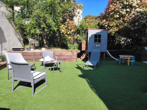 une cour arrière avec une aire de jeux avec des chaises et une maison de jeu dans l'établissement La petite maison, à La Celle-sous-Gouzon
