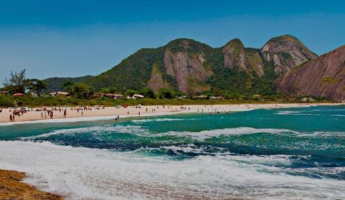 a group of people on a beach near the water at Apartamento moderno, e aconchegante em Icaraí! in Niterói