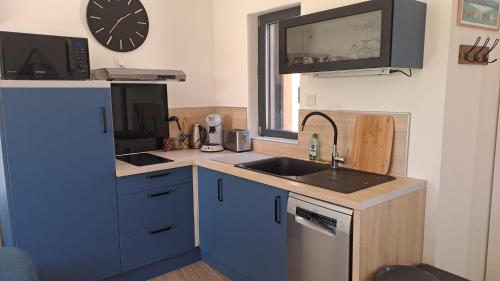 une cuisine avec un évier et une horloge murale dans l'établissement Logement neuf à 2 pas du lac, à La Bridoire