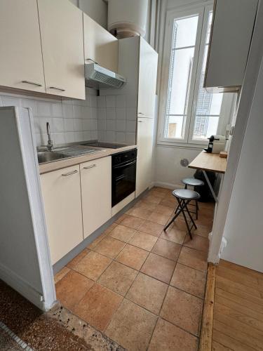 une cuisine avec des armoires blanches et un sol carrelé dans l'établissement Liberation Cozy Studio in Nice, à Nice