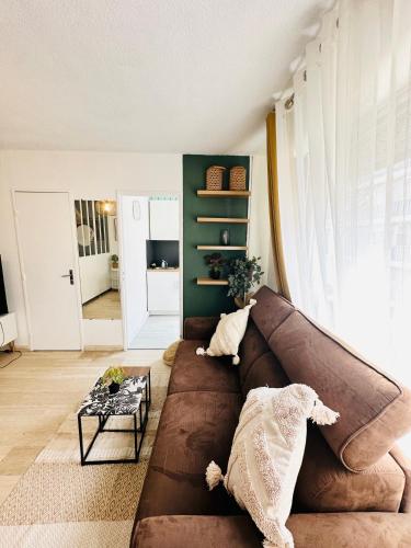 un salon avec un canapé marron et une table dans l'établissement Studio T1- 2 min des Plages - Golf-Juan - Clim&Wifi, à Vallauris