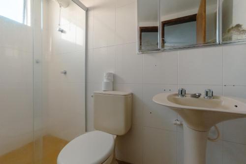a white bathroom with a toilet and a sink at Apartamento Central Aconchegante e Espaçoso SQ53 in Maringá