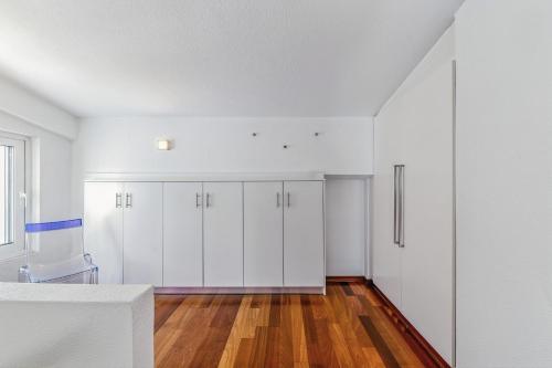an empty kitchen with white cabinets and wood floors at Sea View Residence Panorama Villa in Saronida