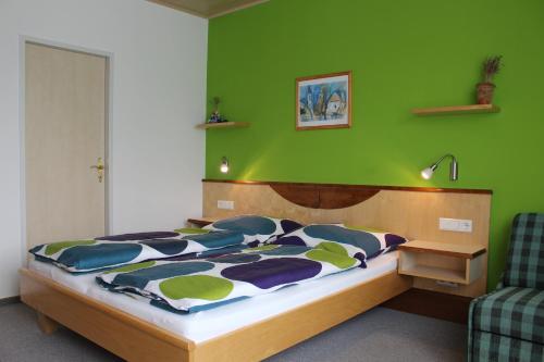 ein Schlafzimmer mit einem Bett mit einer grünen Wand in der Unterkunft Gästehaus Karassowitsch in Rust