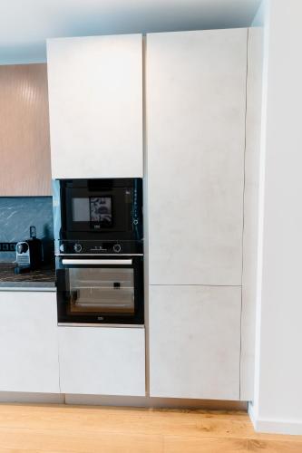 a kitchen with white cabinets with a microwave at Evo Residence Taietura Turcului in Cluj-Napoca