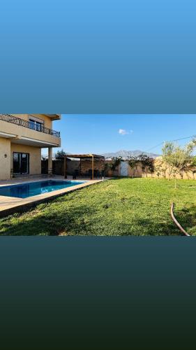 a house with a swimming pool next to a field at Peaceful Pool Villa in Marrakech