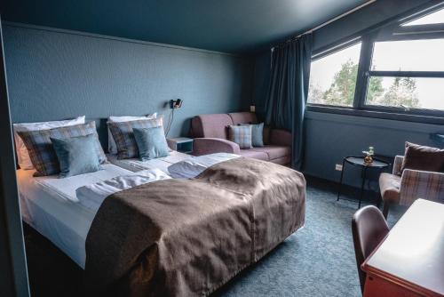 a bedroom with a bed and a chair and a window at Trolltun Hotel & Hytter in Dombås