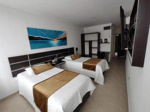 a hotel room with two beds and a tv at Hotel Andinos Plaza Florencia in Florencia