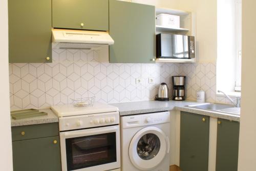 une cuisine avec des armoires vertes et une machine à laver dans l'établissement Chez Céline, plein centre ville, à Narbonne