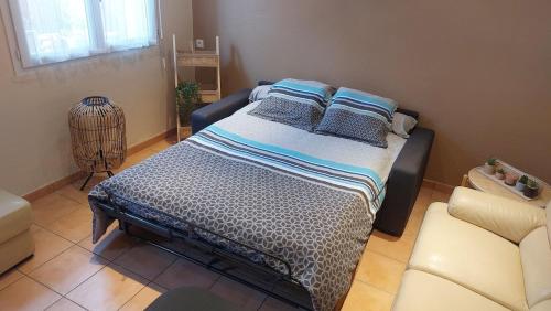 une chambre avec un lit, un canapé et une chaise dans l'établissement Charmant T2 à 5min des plages, à Port-la-Nouvelle