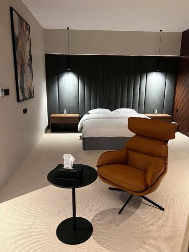 a bedroom with a bed and a chair and a table at شاليهات اصالة فيلا الفندقية in Buraydah