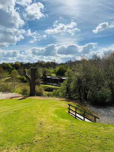 a park with a bench and a train in the distance at Lydeard Farm Bush Camp & Lodges in Bridgwater