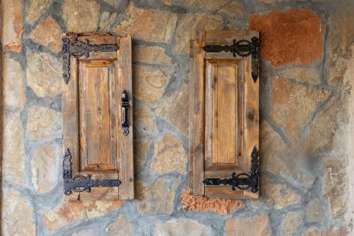 two wooden windows on the side of a stone wall at MANOS Small House Kouremenos in Palekastron