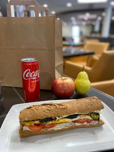 a sandwich on a plate with apples and a can of coke at Hotel Camelia in Cameri