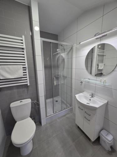 a bathroom with a toilet and a shower and a sink at Apartamenty Emilia 3 in Gniezno