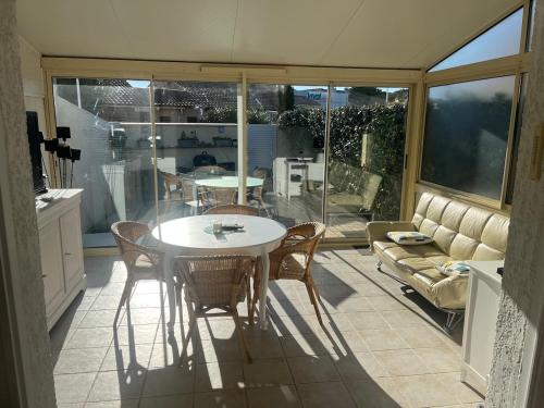 une cuisine avec une table, des chaises et un canapé dans l'établissement Maison rivage bleu 4 pers 2 sdb clim wifi, à Gruissan