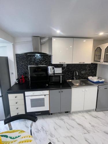 une cuisine avec des armoires blanches et un comptoir noir dans l'établissement Maison calme et lumineuse, à Deuil-la-Barre