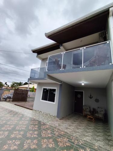 a house with a balcony with people sitting on it at Sobrado Lar Doce Mar Itapoá 100m from the Sea in Itapoa