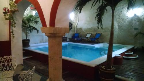 a pool in a house with a palm tree at Hotel Maya Ah Kim Pech in Campeche