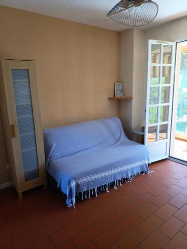a bed in a room with a blue blanket at AGRÉABLE STUDIO cabine PROCHE MER in La Londe-les-Maures