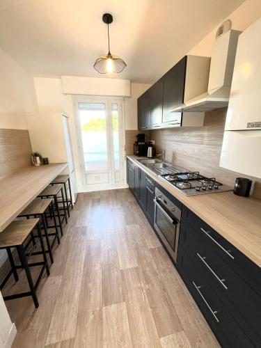 une cuisine avec des armoires noires et un plancher en bois dans l'établissement Le refuge urbain proche des plages, à Lorient