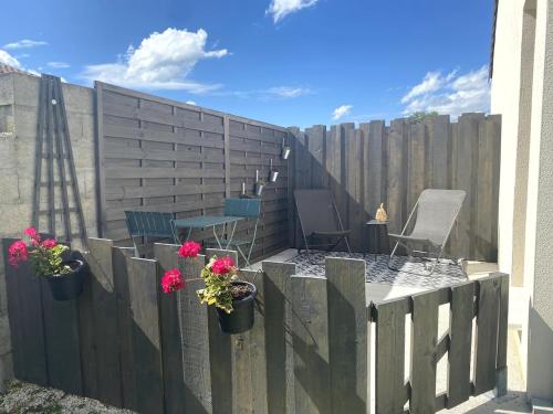 a fence with potted flowers and a table and chairs at Studio 20 minutes des plages in Cissac-Médoc