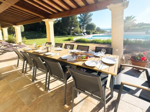 une grande table et des chaises en bois sur la terrasse dans l'établissement Exclusive Authentic Riviera Villa - Private Pool, Pétanque Court, Panoramic Mediterranean Sea & Estérel Mountain Views, à Saint-Raphaël