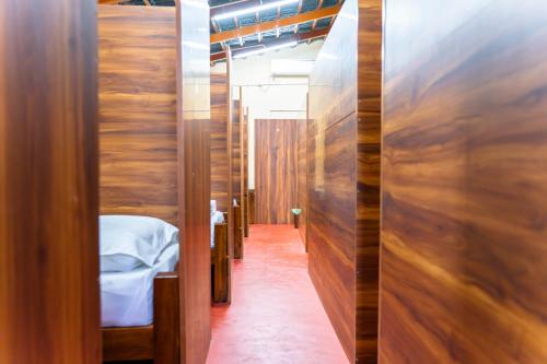 a corridor of a room with a bed and wooden walls at Leo Vishroam in Mysore