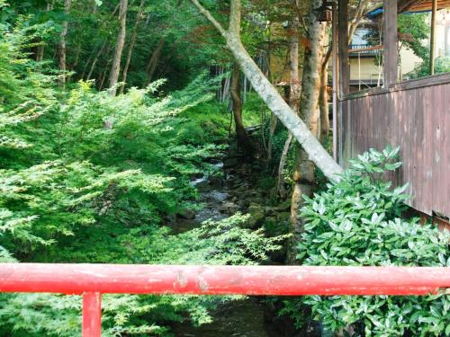 a red bench in a garden with a stream at Iwasu-so in Nakatsugawa