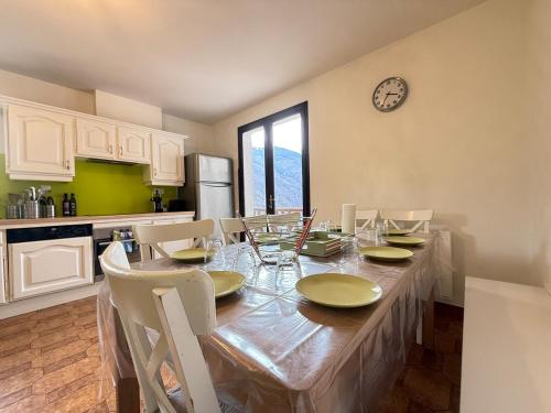 une cuisine avec une table, des chaises et une horloge murale dans l'établissement Duplex 15 Pers-Proche Grands Cols-Garage, à Saint-Martin-de-la-Porte