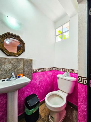 a pink bathroom with a toilet and a sink at Maya Dreams Bacalar in Bacalar